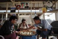 People play chess near pictures of pro-democracy leader Aung San Suu Kyi and her father and country's independence hero General Aung San at a market in capital Naypyitaw, January 24, 2012.