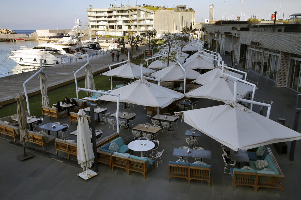 This Wednesday, Dec. 18, 2019 photo, people sitting at the almost empty restaurant, in Beirut, Lebanon. Lebanon's unprecedented economic crisis and two months of mass protests have taken a huge toll on hotel and restaurant industries, with massive losses reported by various businesses. (AP Photo/Bilal Hussein)