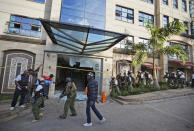 Security forces surround a hallway behind a shattered door in which an unexploded grenade lies, at a hotel complex in Nairobi, Kenya Tuesday, Jan. 15, 2019. Terrorists attacked an upscale hotel complex in Kenya's capital Tuesday, sending people fleeing in panic as explosions and heavy gunfire reverberated through the neighborhood. (AP Photo/Ben Curtis)