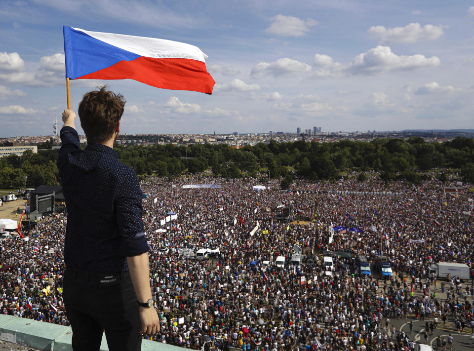 A man waves the Czech flag as people protest in Prague, Czech Republic, Sunday, June 23, 2019. Protesters are on calling on Czech Prime Minister Andrej Babis to step down over fraud allegations and subsidies paid to his former companies. (AP Photo/Petr David Josek)