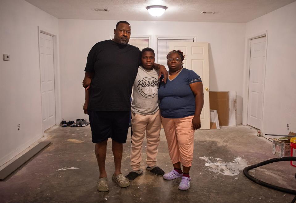 Jimmy Lee Kelly Jr., Jimmy Lee Kelly III and Pamela Denise Kelly pose for a portrait in their living room in Jackson on Friday, Nov. 10. They had to rip out the floorboards and throw away all their furniture that was touched by raw sewage.