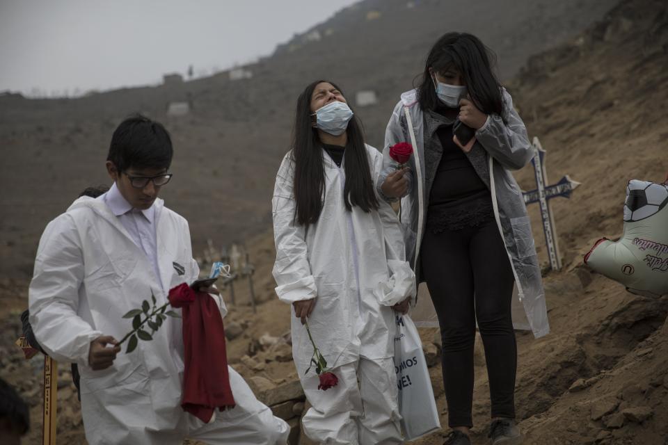 Dayra Montalbo, 12, center, cries next to her sister Valeria, 18, and brother Carlos, 16, during the burial of their father Carlos Montalbo, 45, who died of COVID-19 complications, at the Nueva Esperanza cemetery on the outskirts of Lima, Peru, Thursday, May 28, 2020. Carlos Montalbo Sr. died at his home after calls from his relatives to the Health Ministry went unanswered. (AP Photo/Rodrigo Abd)