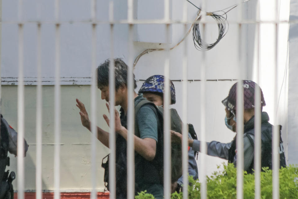 In this Feb. 26, 2021, photo, Japanese journalist Yuki Kitazumi raises his hands as he is escorted by police upon arrival at the Myaynigone police station in Sanchaung township in Yangon, Myanmar. Japan's government said Monday, April 19, 2021 it is asking Myanmar to release the Japanese journalist who was arrested by security forces in its largest city of Yangon the previous day. (AP Photo)