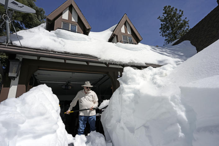 John Bays clears snow off his driveway after a series of storms, Wednesday, March 8, 2023, in Lake Arrowhead, Calif. (AP Photo/Marcio Jose Sanchez)