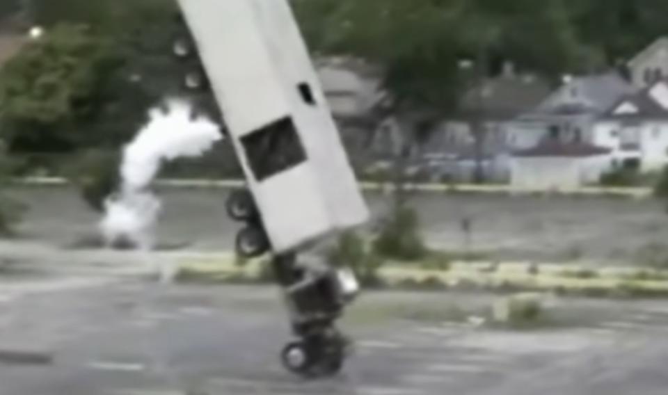 A semi truck is mid-air, being flipped upside-down