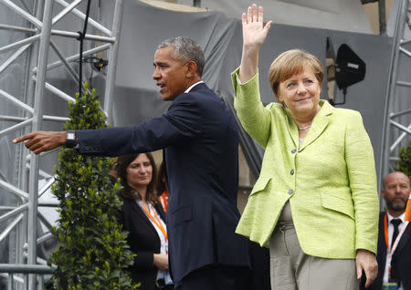 German Chancellor Angela Merkel and former U.S. President Barack Obama wave at the end of a discussion at the German Protestant Kirchentag in front of the Brandenburg Gate in Berlin. REUTERS/Fabrizio Bensch