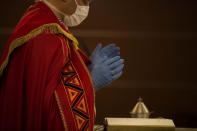 A priest wearing a mask and gloves celebrates Mass at the Ospedale di Circolo in Varese, Italy, Friday, April 10, 2020. The new coronavirus causes mild or moderate symptoms for most people, but for some, especially older adults and people with existing health problems, it can cause more severe illness or death. (AP Photo/Luca Bruno)