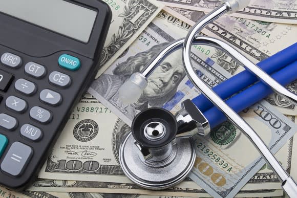 Stethoscope and calculator on top of dollar bills.