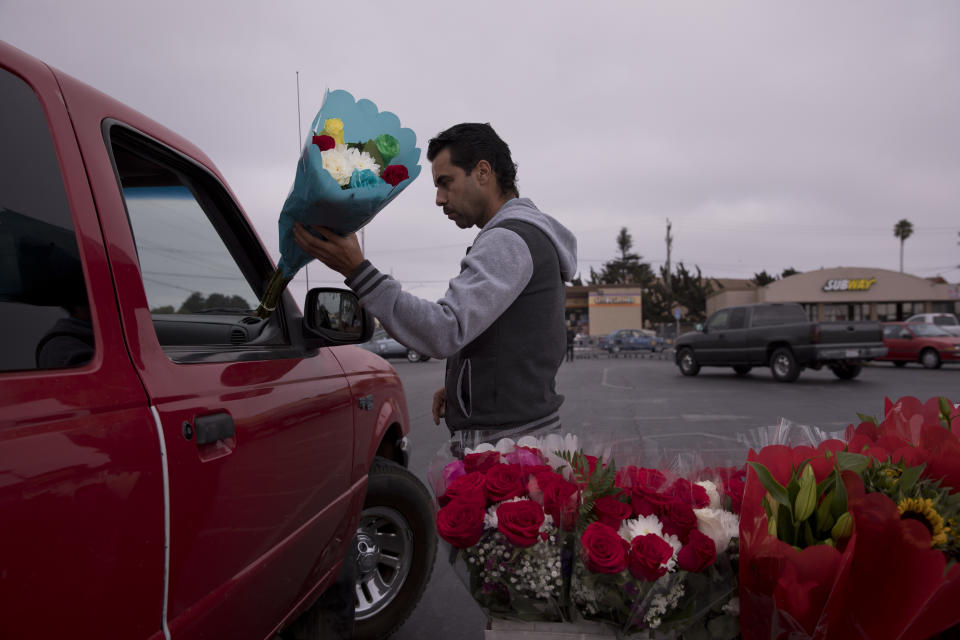 In this Tuesday, Sept. 4, 2018, photo, Jose Contrares, who shares an apartment with seven people, sells flowers in the parking lot of a strip mall in Salinas, Calif. Few cities exemplify California's housing crisis better than Salinas, an hour's drive from Silicon Valley and surrounded by farm fields. It's one of America's most unaffordable places to live, and many residents believe politicians lack a grip on the reality of the region's housing crisis. (AP Photo/Jae C. Hong)