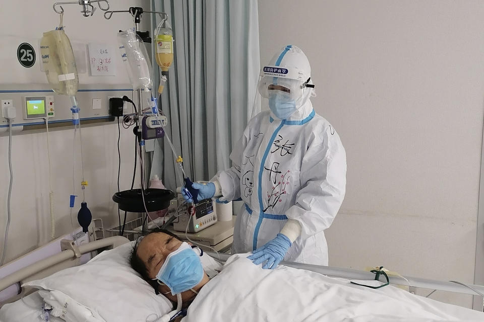 In this photo released by Chinese nurse Zhang Dan, she looks after a patient being treated for COVID-19 at the Tongji hospital in Wuhan in central China's Hubei province Monday, March 9, 2020. Zhang was among the first to respond to the call for help in China's coronavirus epicenter. The 36-year-old nurse worked through grueling days, ministering to patients who needed assistance from breathing to merely eating. She struggled — but then, a little street dog helped her through. (Zhang Dan via AP)