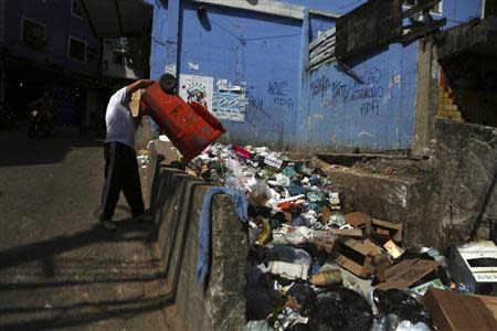 A man throws his garbage along a street at the Rocinha slum in Rio de Janeiro March 13, 2014. REUTERS/Pilar Olivares