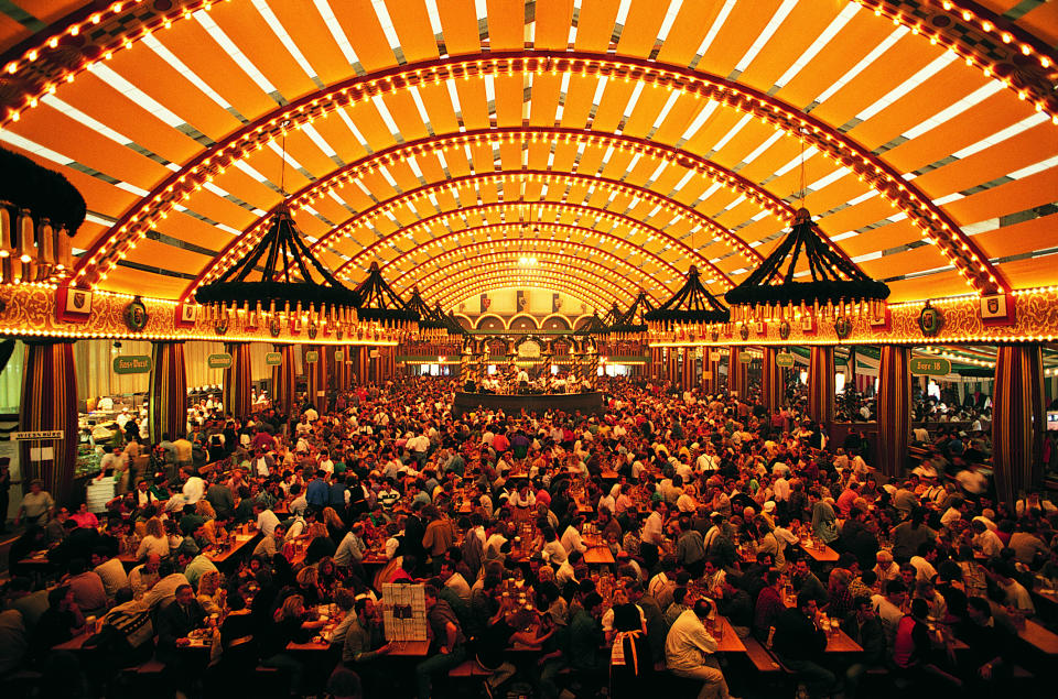 A large crowd gathers in a festively decorated hall with arched, illuminated ceilings, appearing to be celebrating at a large indoor event or festival