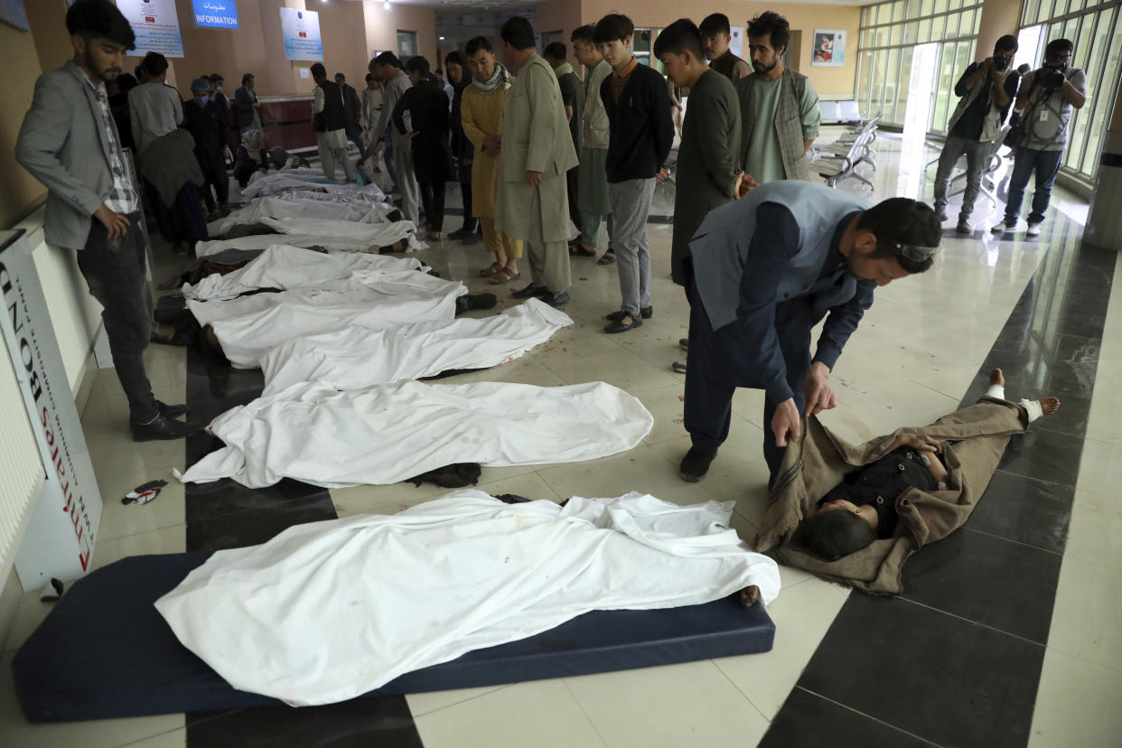 Afghan men try to identify the dead bodies at a hospital after a bomb explosion near a school west of Kabul, Afghanistan, Saturday, May 8, 2021. A bomb exploded near a school in west Kabul on Saturday, killing several people, many them young students, an Afghan government spokesmen said. (AP Photo/Rahmat Gul)