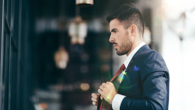 Smiling businessman fixing his necktie before going out.