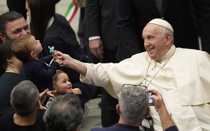 Pope Francis jokingly takes the pacifier from a child in the Paul VI Hall at the Vatican at the end of his weekly general audience, on Dec. 14. Pope Francis called on Wednesday for a “humble” Christmas this year, with reduced spending on gifts and for the savings to be donated instead to help the “suffering people of Ukraine.” <em>Associated Press/Domenico Stinellis</em>