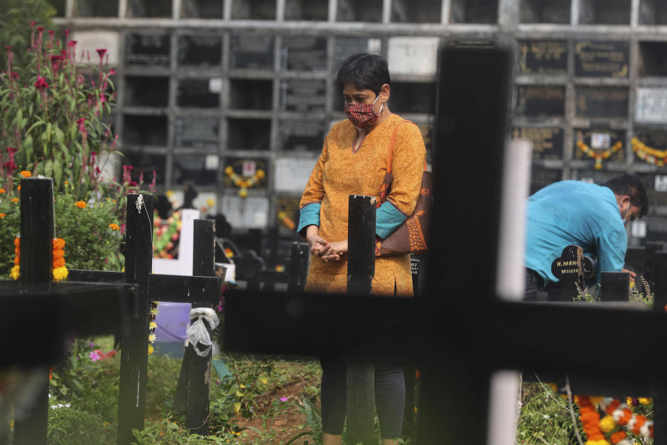 A woman wearing face mask as a precaution against the coronavirus prays at the grave of a deceased relative during All Souls Day in Mumbai, India, Monday, Nov. 2, 2020. (AP Photo/Rafiq Maqbool)