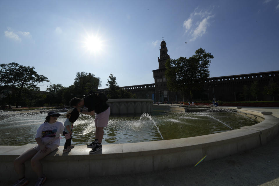 Tourists cool off in a public fountain at the Sforzesco Castle, in Milan, Italy, Saturday, July 15, 2023. Temperatures reached up to 42 degrees Celsius in some parts of the country, amid a heat wave that continues to grip southern Europe. (AP Photo/Luca Bruno)