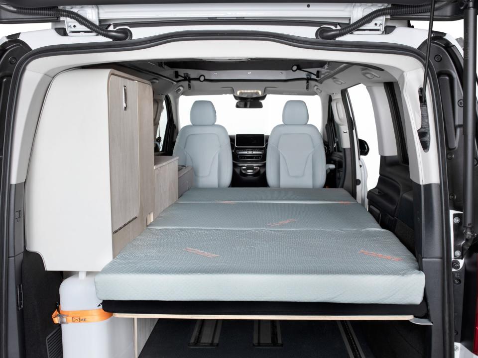 A large mattress open across the van behind the two front seats.