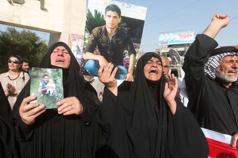 Iraqi women hold pictures of their relatives -- who are believed to have been killed in the Speicher massacre -- during a demonstration in Baghdad, on April 27, 2015