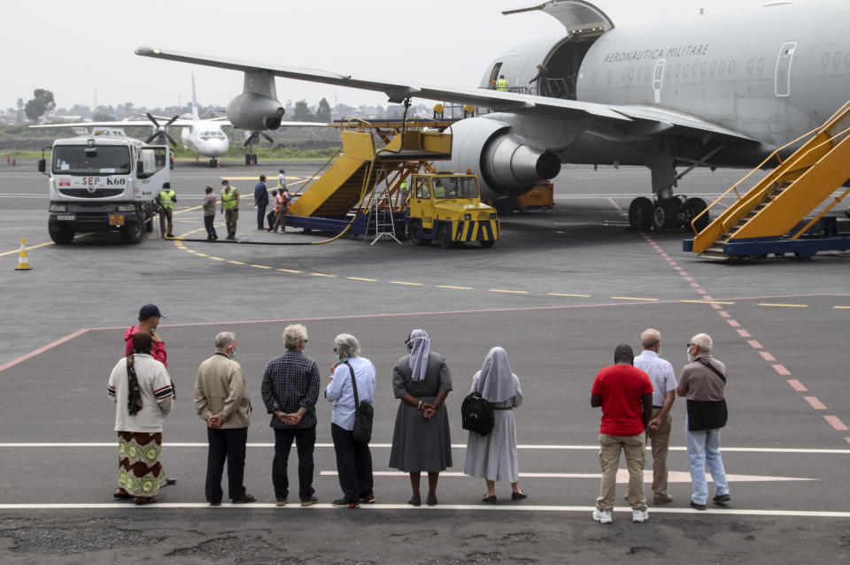 Unidentified people observe the airplane after it arrived to transport the bodies of Italian ambassador to Congo Luca Attanasio and Carabinieri officer Vittorio Iacovacci to the capital Kinshasa, at the airport in Goma, North Kivu province, Congo Tuesday, Feb. 23, 2021. Congo has dispatched a team to support investigators on the ground in Goma where the Italian ambassador to Congo, an Italian Carabinieri police officer and their driver were ambushed and killed Monday. (AP Photo/Justin Kabumba)