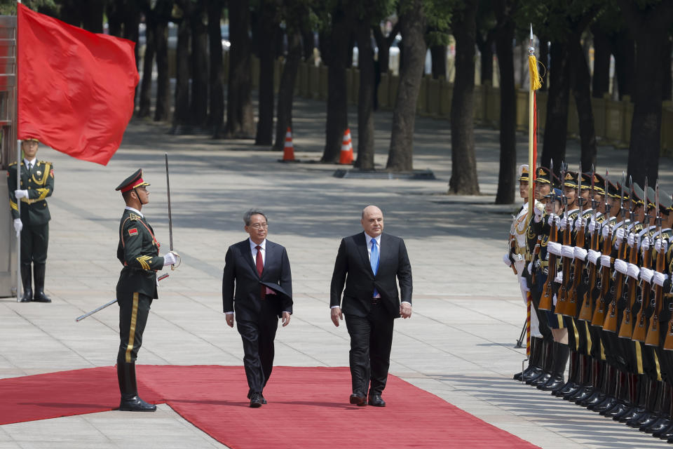 Russian Prime Minister Mikhail Mishustin, center right, and Chinese Premier Li Qiang attend a welcoming ceremony in Beijing, China, Wednesday, May 24, 2023. (Thomas Peter/Pool Photo via AP)