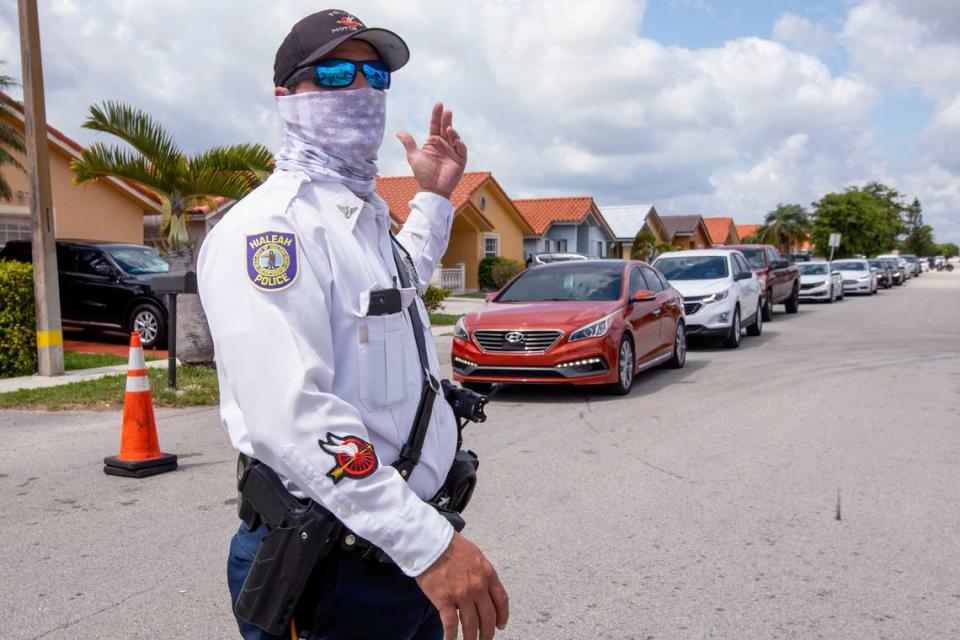 Hialeah police officer Romeo Morales directs several residents as they line up to receive unemployment applications Slade Park in Hialeah on Tuesday.