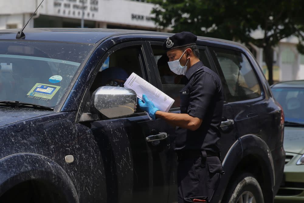 A police personnel conducts checks on a vehicle during a roadblock in Kuala Lumpur March 31, 2020. — Picture by Yusof Mat Isa