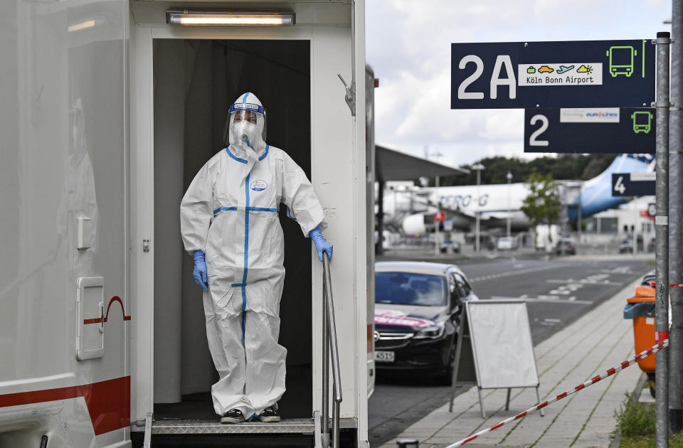 Medical staff wait for travelers to take COVID-19 tests from arriving passengers at the airport in Cologne, Germany, Tuesday, July 28, 2020. New test centers for coronavirus are established at German airports due to the pandemic and free corona tests are given for returnees from countries designated as risk areas. (AP Photo/Martin Meissner)