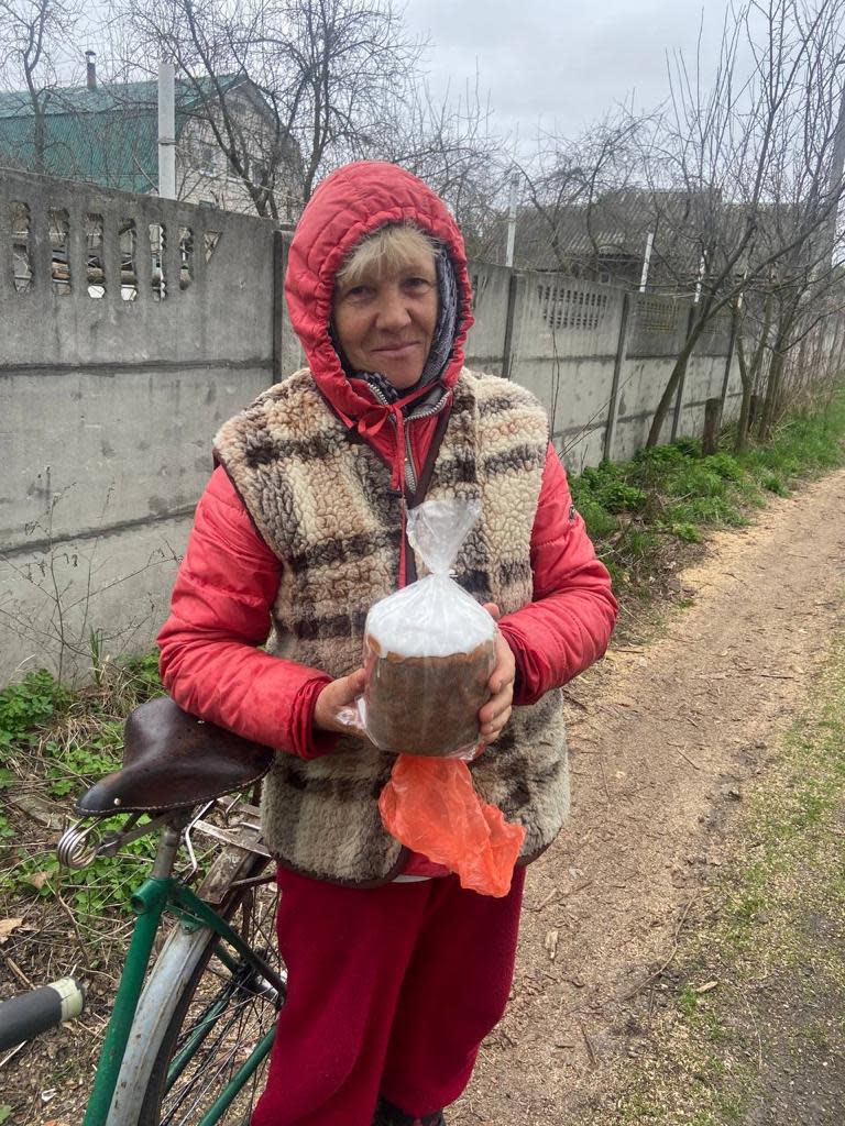 A woman in Ukraine takes a loaf of Easter paska made by Bakehouse in April 2022.