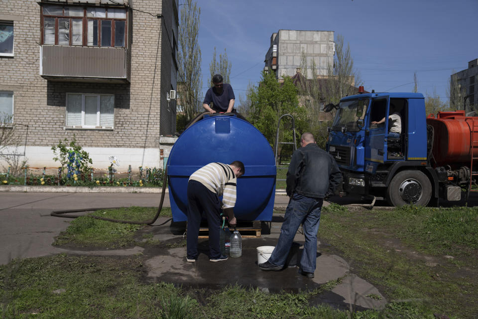 Local residents fill cans with water from a water tank installed for residents of Toretsk, eastern Ukraine, Monday, April 25, 2022. Toretsk residents have had no access to water for more than two months because of the war. (AP Photo/Evgeniy Maloletka)