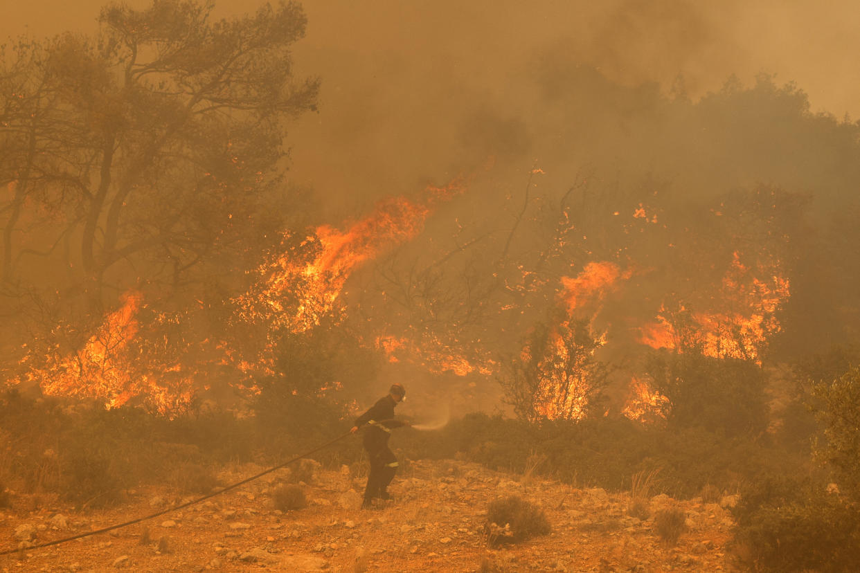 A firefighter tries to extinguish a wildfire burning near the village Vlyhada