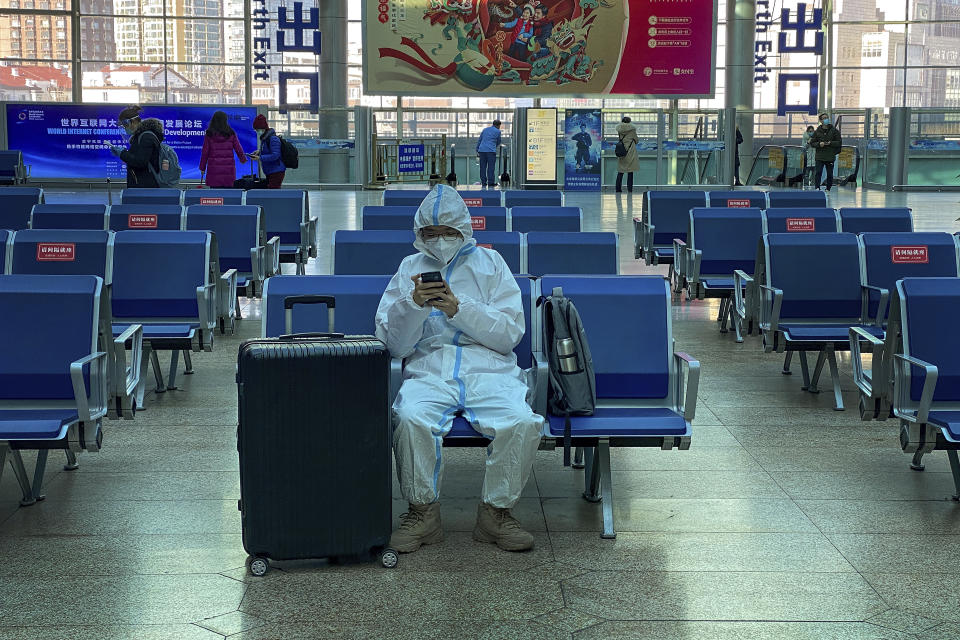 A traveller wearing protective gear to help curb the spread of the coronavirus sits alone on the bench as he waits for his train at the South Train Station in Beijing, Thursday, Jan. 28, 2021. Efforts to dissuade Chinese from traveling for Lunar New Year appeared to be working. Beijing's main train station was largely quiet on the first day of the travel rush and estimates of passenger totals were smaller than in past years. (AP Photo/Andy Wong)