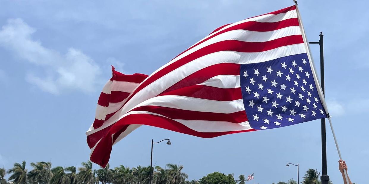 Ben Polluck, who was a protestor on January 6, holds a flag upside down outside Mar-a-Lago.