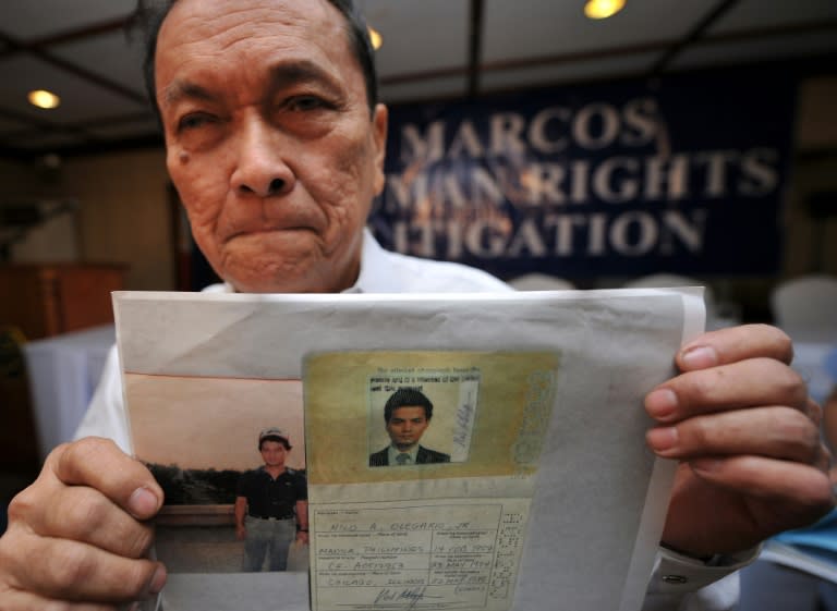 Retired Philippine air force colonel Nilo Olegario holds a photo of his namesake and activist son prior to receiving compensation cheque of the first batch of human rights victims under the late dictator Ferdinand Marcos