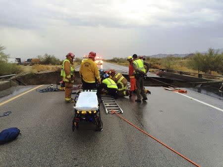 Emergency personnel tend to the victim of a car that fell into a collapsed section of a bridge on the eastbound Interstate 10 freeway west of Desert Center, California, in this July 19 handout photo released July 20, 2015. Heavy rains undermined the bridge along the heavily traveled route from California to Arizona, closing traffic in both directions indefinitely. REUTERS/Division Chief Geoff Pemberton & CAL FIRE/Riverside County Fire/Handout via Reuters