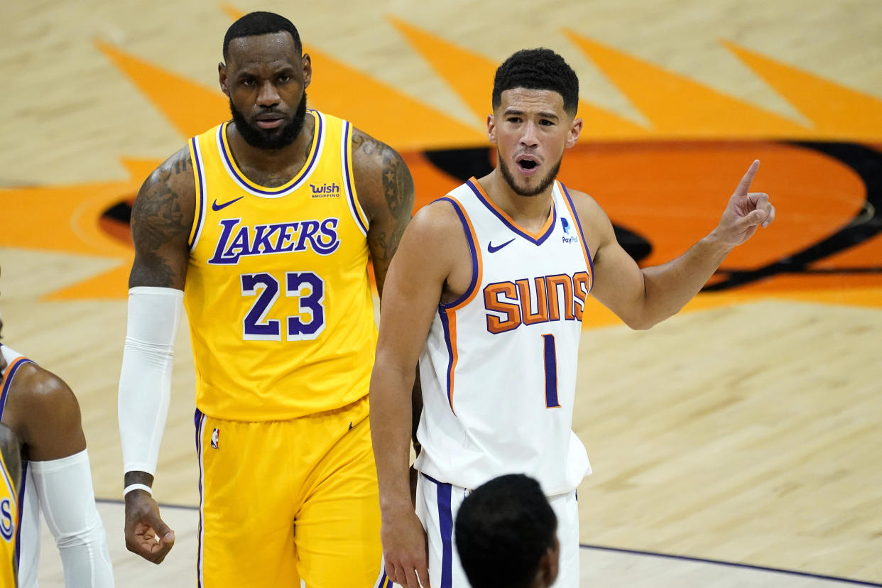 Los Angeles Lakers forward LeBron James (23) and Phoenix Suns guard Devin Booker (1) during the first half of a preseason basketball game, Friday, Dec. 18, 2020, in Phoenix, Ariz. (AP Photo/Matt York)