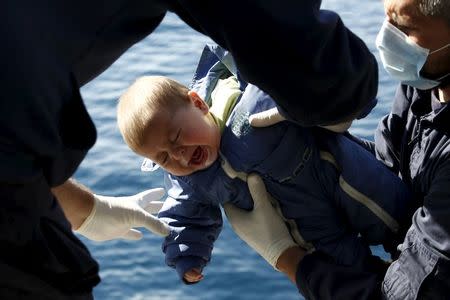 Greek Coast Guard officers move a baby from a dinghy carrying refugees and migrants aboard the Ayios Efstratios Coast Guard vessel, during a rescue operation in the open sea between the Turkish coast and the Greek island of Lesbos, February 8, 2016. REUTERS/Giorgos Moutafis