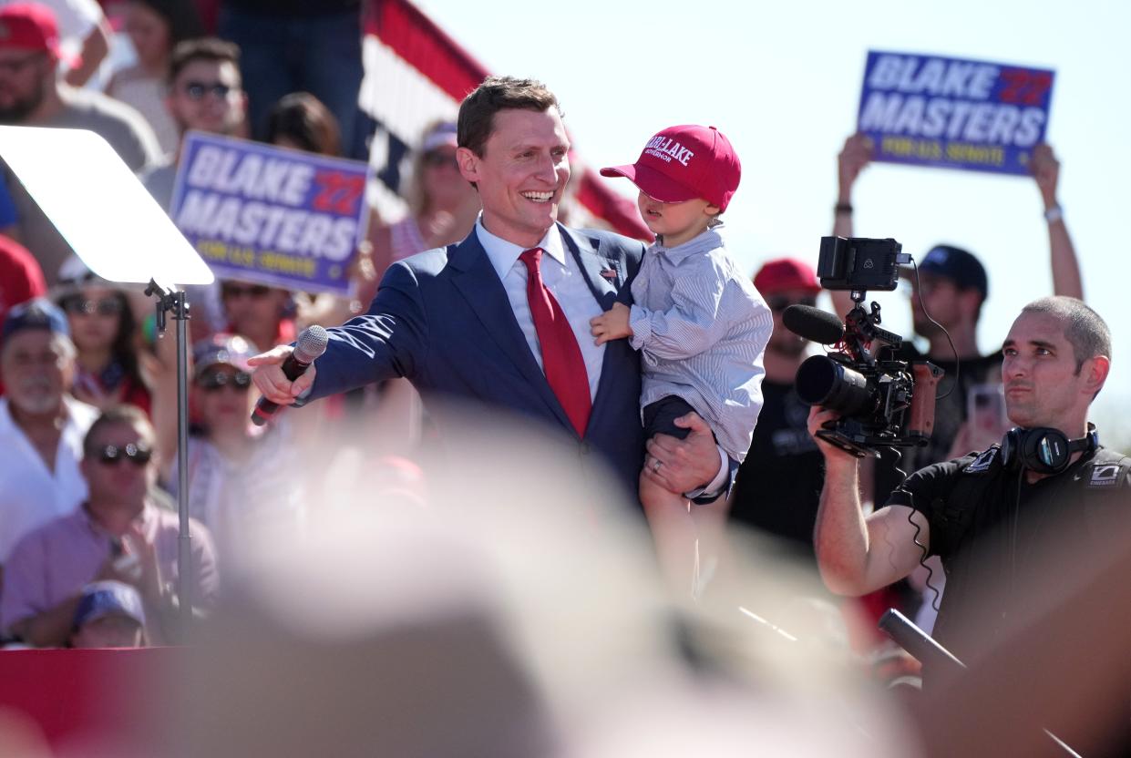 Republican Senate Candidate Blake Masters holds his 2-year-old son Rex as he greets people gathered at Legacy Sports Park on Oct. 9, 2022, before a speech by former President Donald Trump.