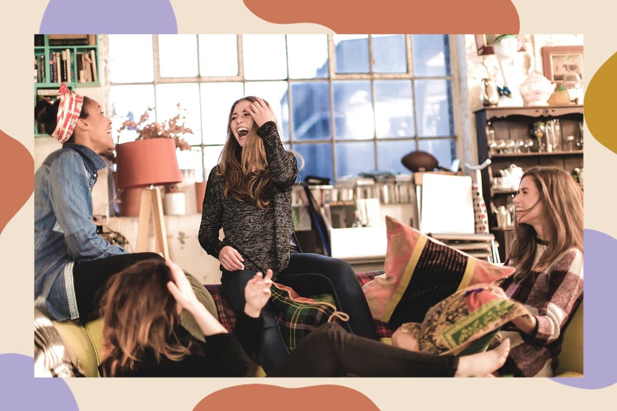 Group of four women laughing and sitting on a couch.