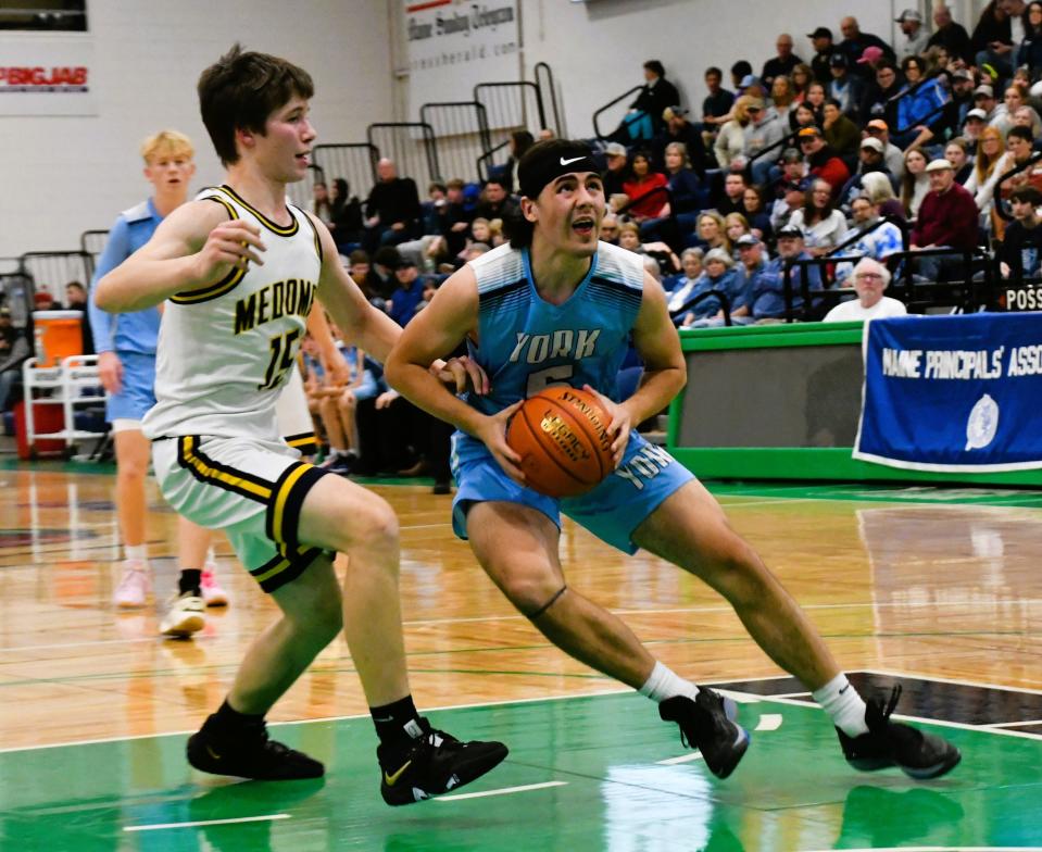 York’s Jake Fogg, right, eyes the hoop as he is defended by Medomak’s Valley’s Kory Donlin