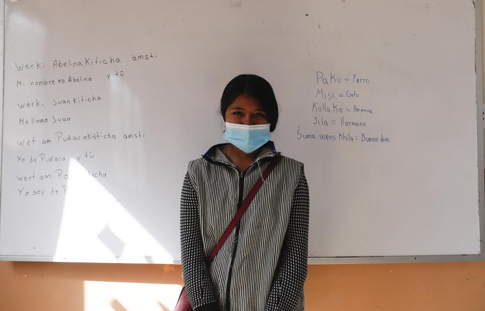 Abelina Choque stands inside her classroom next to her work, left, she wrote out on a dry erase board, during an Uru language lesson, in the Urus del Lago Poopo indigenous community, in Punaca, Bolivia, Monday, May 24, 2021. “The instructors teach us the language with numbers, songs and greetings,” said Choque, a 21-year-old student who said she one day would like to teach mathematics. “It’s a little difficult to pronounce.” (AP Photo/Juan Karita)