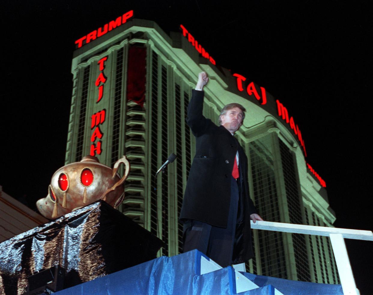 Donald Trump ascends the stairs with his fist raised from the genie's lamp after opening the Trump Taj Mahal Casino Resort in a spectacular show of fireworks and laser lights on Thursday, April 5, 1990, in Atlantic City, N.J.
