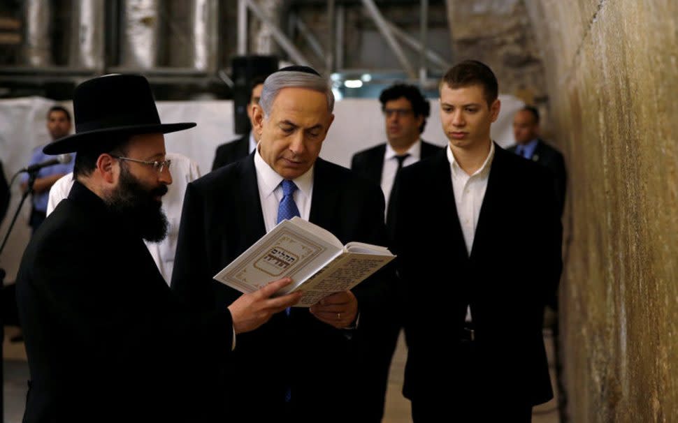 Benjamin Netanyahu (C) reads a prayer with Western Wall Rabbi Shmuel Rabinowitz (L) as his son Yair (R) stands next to him, at the Western Wall, Judaism's holiest prayer site, in Jerusalem's Old City March 18, 2015. - Reuters