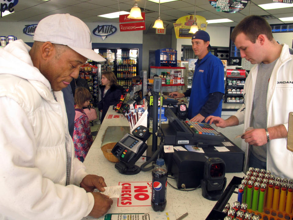 Michael Arrington, left, buys a Powerball ticket from cashier Lee Heilig, right, on Friday, Nov. 23, 2012, at a DeliMart convenience store in Iowa City, Iowa. The jackpot had reached $325 million as of Friday. (AP Photo/Grant Schulte)