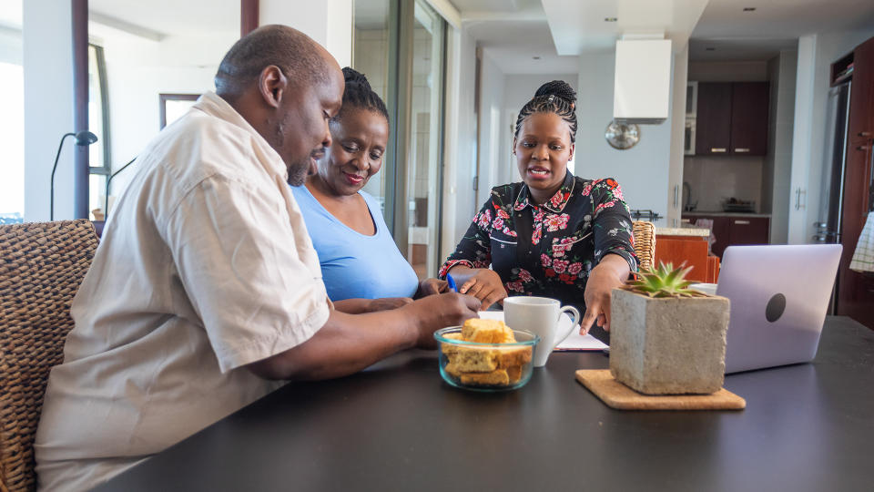 Senior African Couple Getting Retirement Financial Advice at the Dining Room Table.