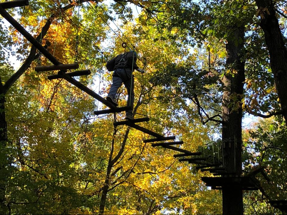 A climber navigates through the trees Oct. 15, 2022, at the Edge Adventure Park at South Bend's Rum Village Park.