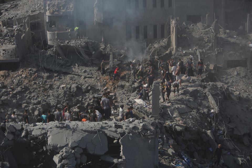 Palestinians look for survivors in the rubble of a destroyed building following an Israeli airstrike (AP)