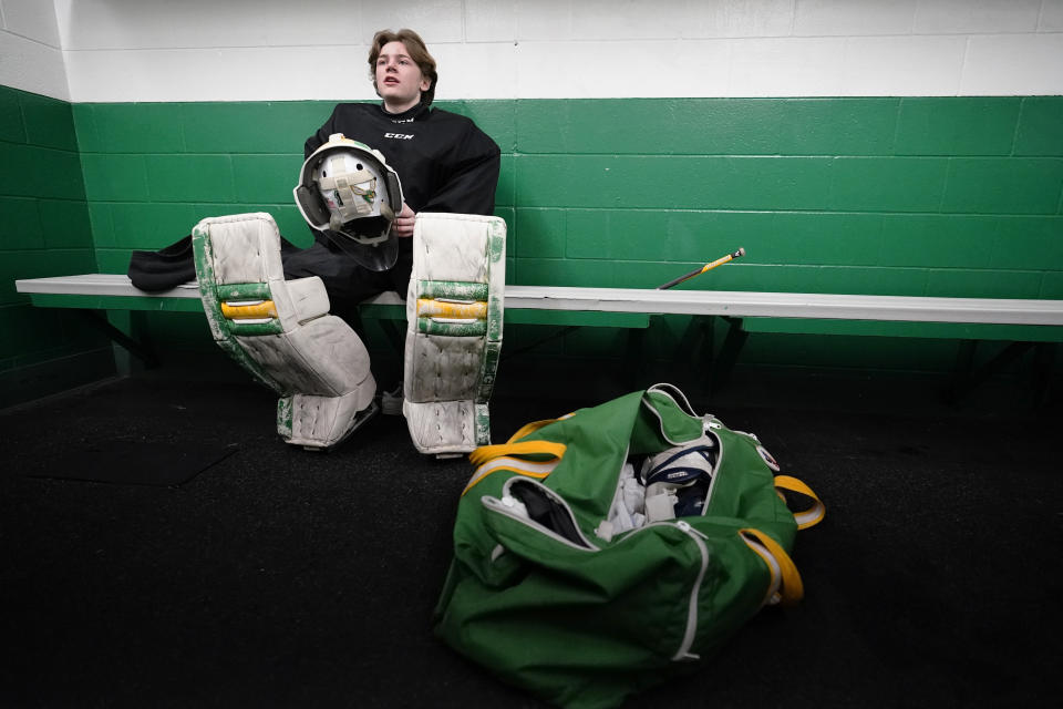 Evan Smolik sits in a dressing room before a hockey practice Thursday, Nov. 29, 2023, in Edina, Minn. When Evan was 14, a teammate's skate struck his neck and his jugular vein, but the neck guard he was wearing prevented the skate from cutting his carotid artery and helped save his life. (AP Photo/Abbie Parr)