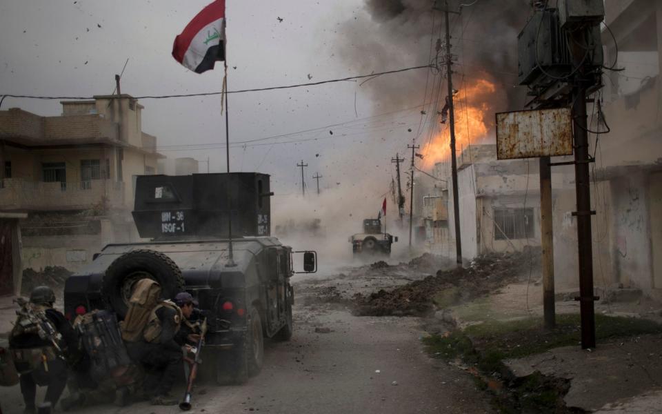 A car bomb exploding next to Iraqi army vehicles during fighting to liberate Mosul - AP