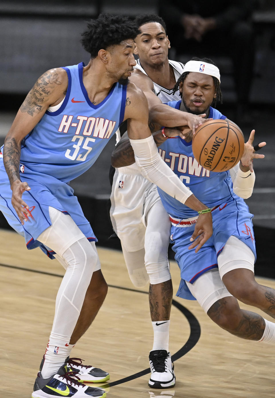 San Antonio Spurs' Devin Vassell, center, pokes the ball from the grasp of Houston Rockets' Ben McLemore, right, as Rockets forward Christian Wood looks on during the first half of an NBA basketball game, Saturday, Jan. 16, 2021, in San Antonio. (AP Photo/Darren Abate)